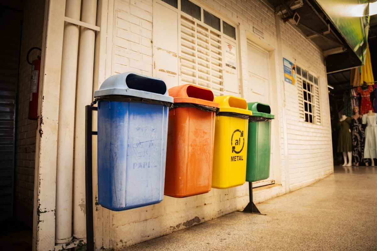 testimonial-img Four recycling bins for different materials in a market setting, emphasizing waste sorting and environmental awareness.