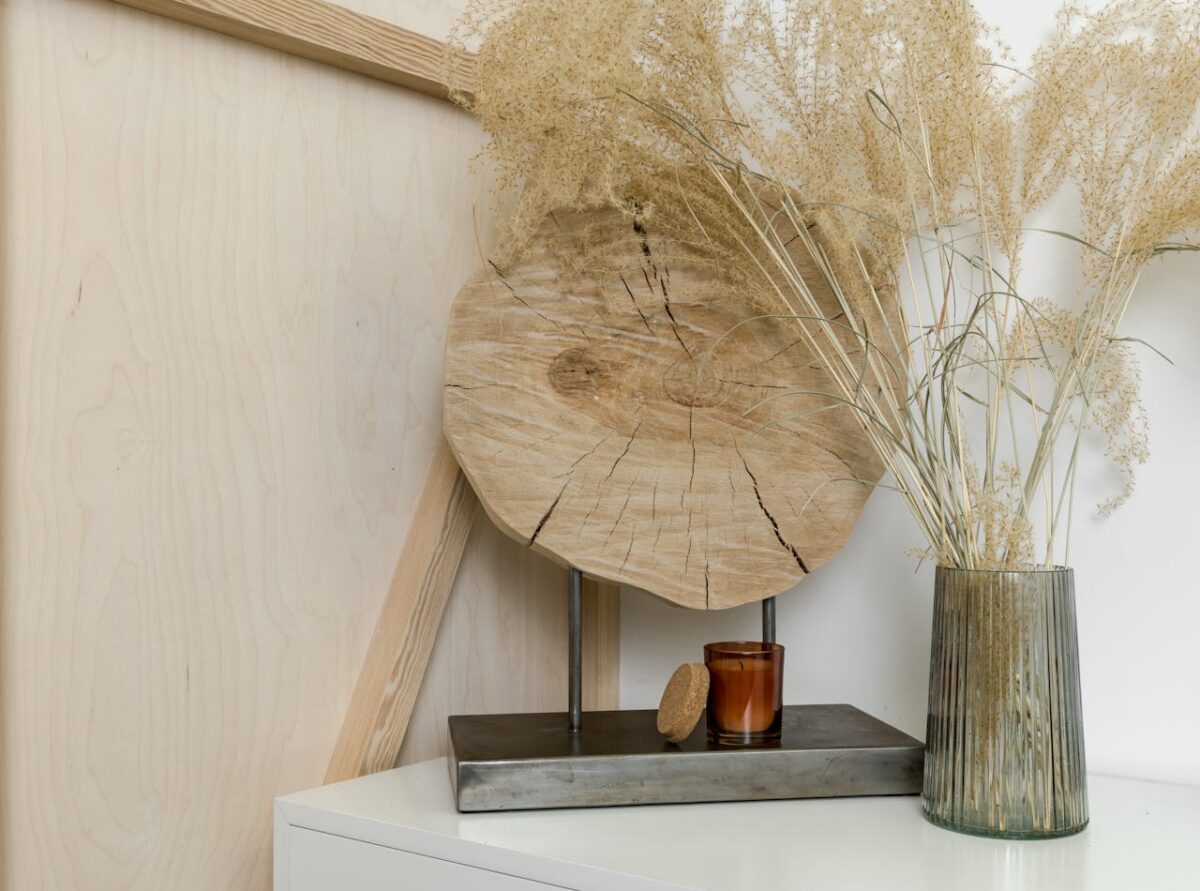 about-01 A stylish interior decor setting featuring dried plants in a glass vase and wooden accents.