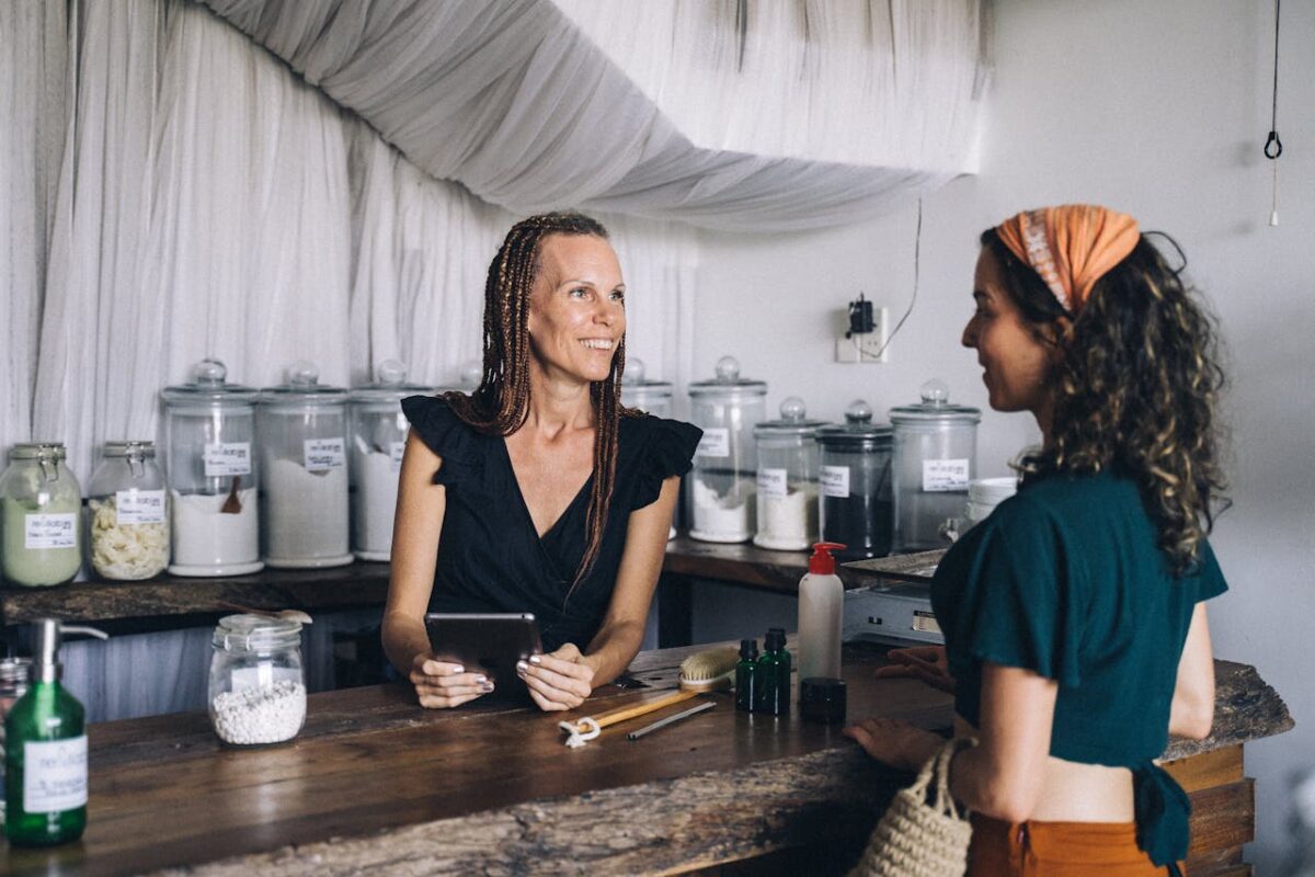service-03 Woman using a tablet to assist customer in eco-friendly store with jars and eco products.